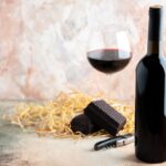 front view glass of wine with bottle and chocolate on light back